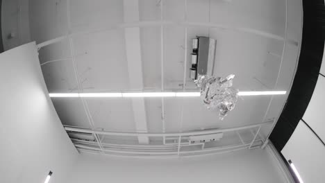 slow-motion abstract video of tinfoil flying through the air in a studio. dynamic motion captured with fisheye lens. shiny metal texture, creative visuals, artistic experimental shot.