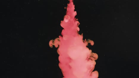 Slow-motion-video-of-pink-watercolor-ink-mixing-in-water-against-black-background