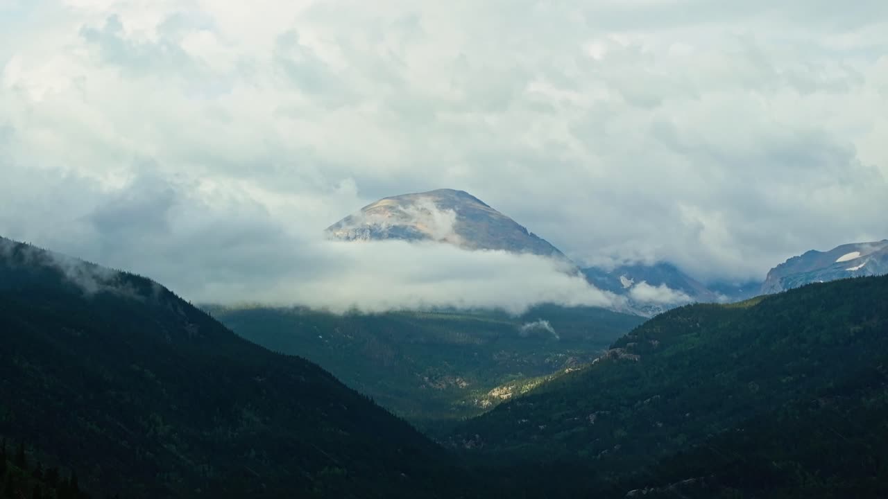 Establishing drone tracking left across rainy mountain ridges and forest valley in Allenspark Colorado, misty scenic backdrop