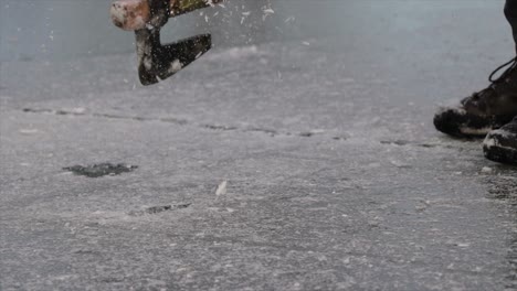 Cutting-ice-of-a-frozen-lake-with-a-big-axe-close-up