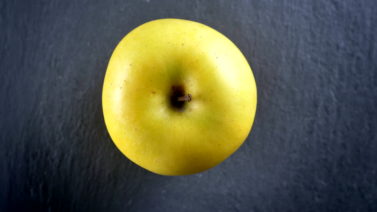 Nærbillede ovenfra af et grønt æble, der snurrer rundt i bevægelse.