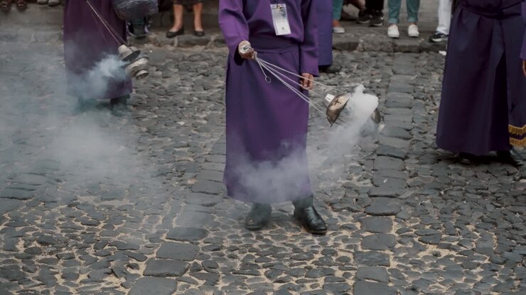 Person In Purple Robe Swinging Thurible With Smoke While Standing In The Cobblestone Street Of Antigua, Guatemala