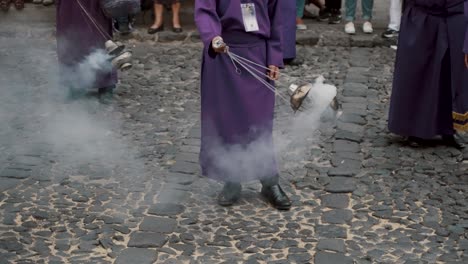 persona con túnica púrpura balanceándose con humo mientras estaba de pie en la calle de adoquines de antigua, guatemala