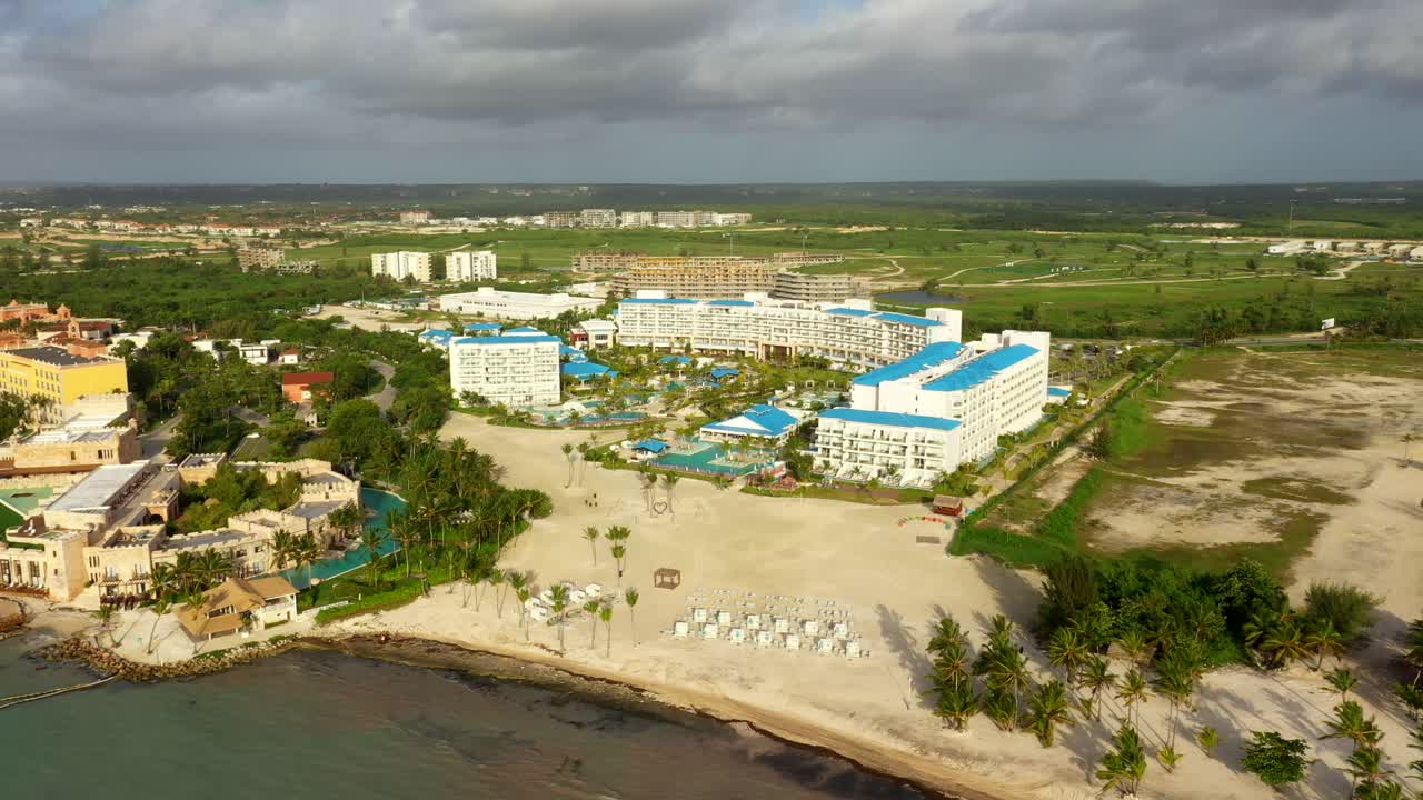 Oceanfront resort aerial with palm lined buildings and coastline, panoramic overview, Cap Cana Juanillo Beach Dominican Republic