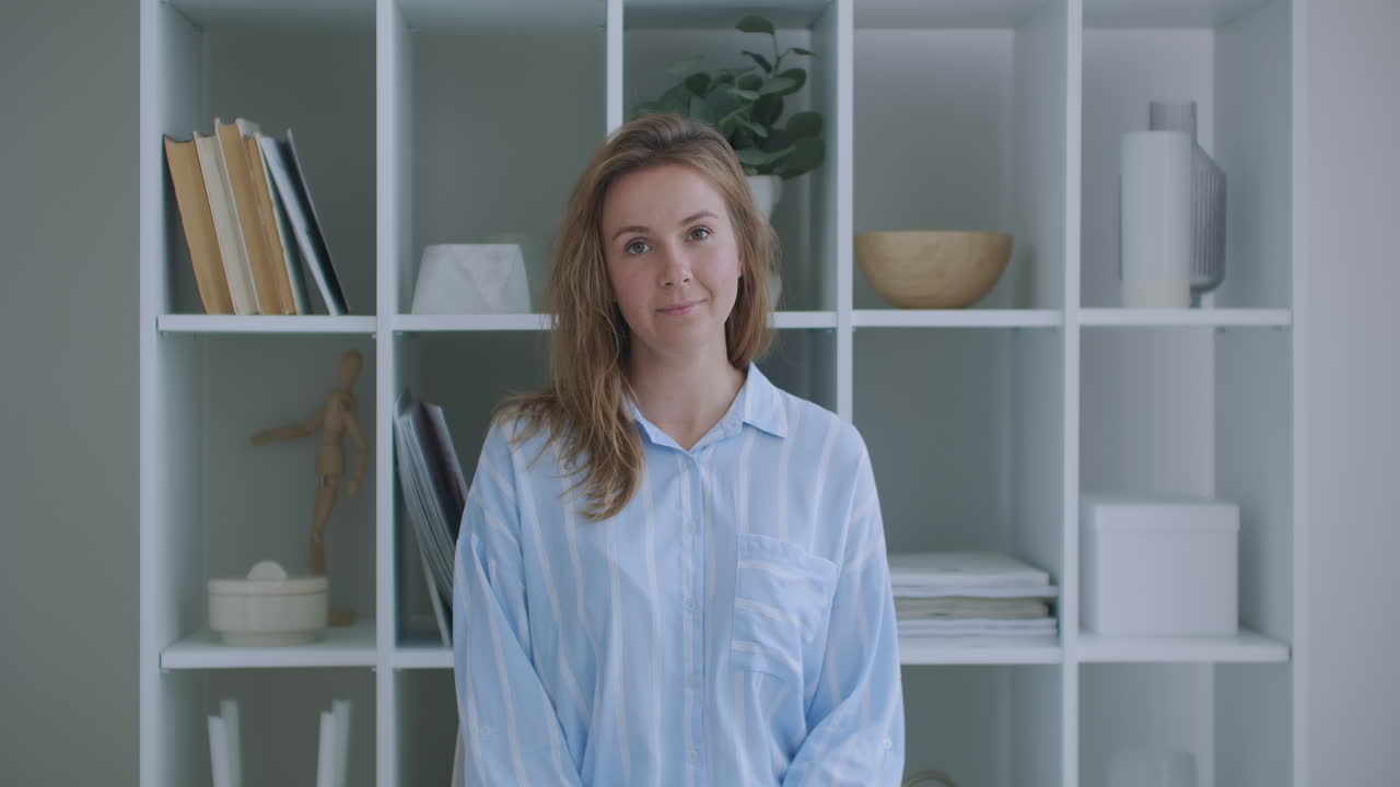 The woman listens while looking at the camera and nods her head approvingly. Participant in the video call dialog. Video conference listener sitting at home