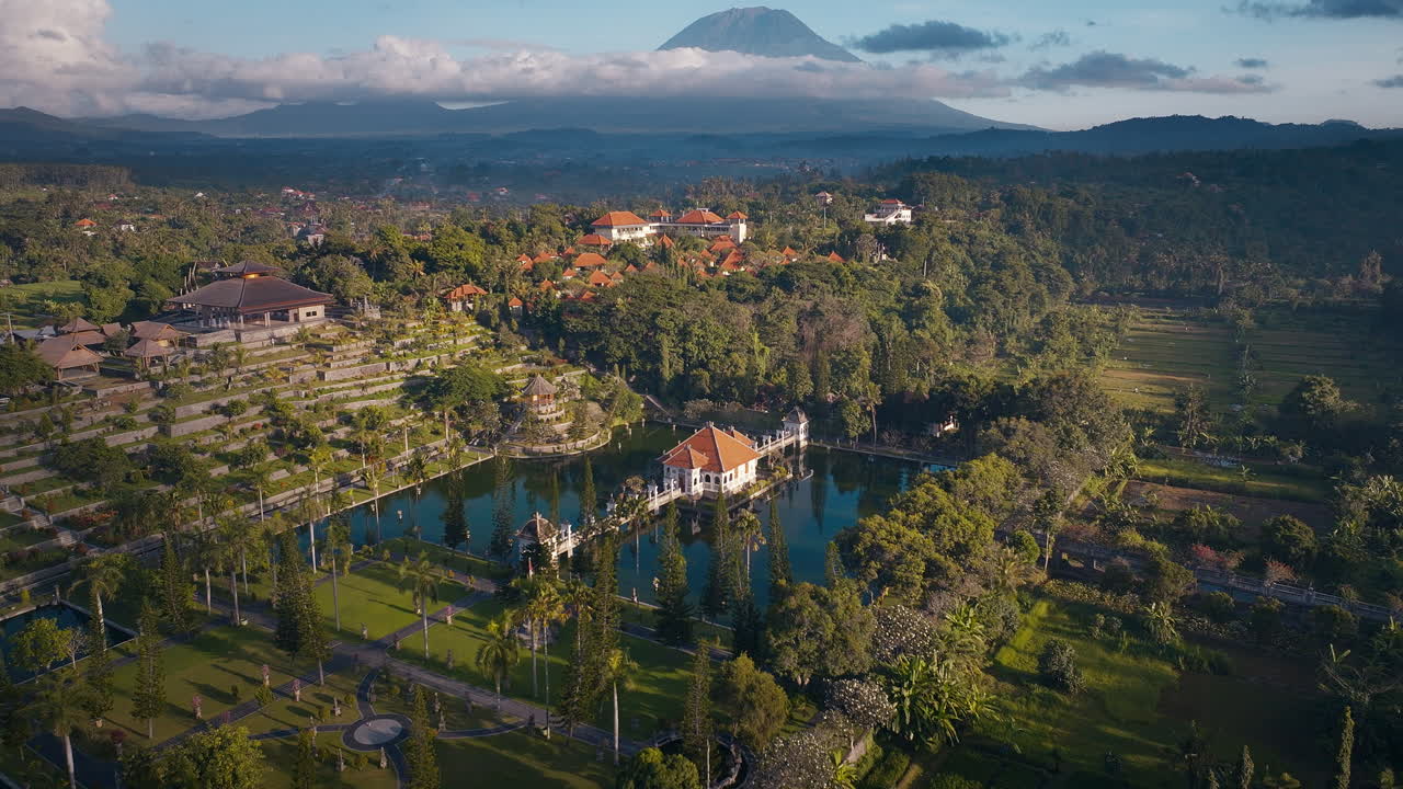 Taman Ujung royal water palace with active volcano mountain Mount Agung in the background at sunset, Bali, Aerial view