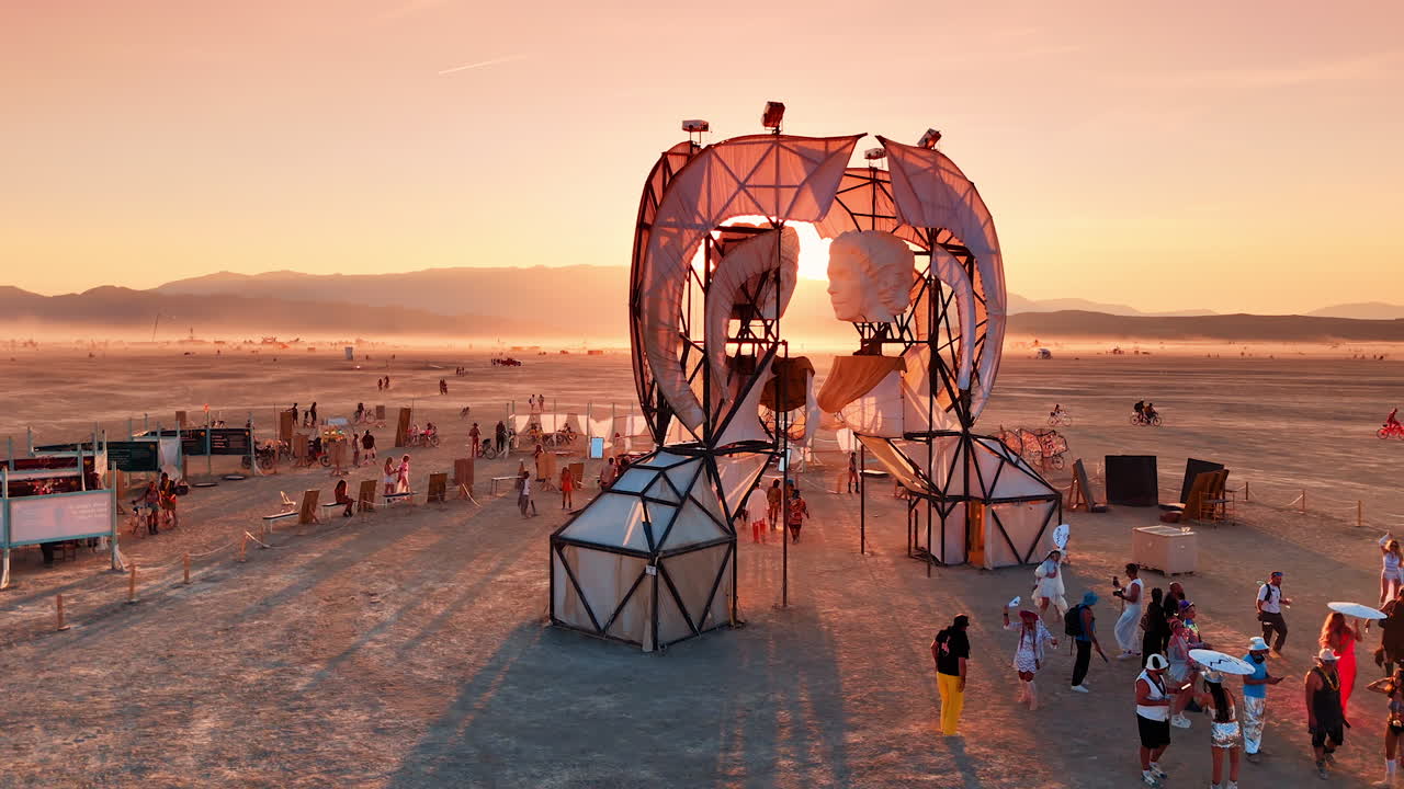 Nevada, USA, 22 August 2025: Burning Man art installation with sunrise light. Large art installation with human faces and tents at Burning Man festival during sunrise