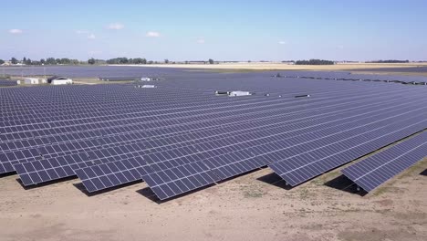 Aerial-rotates-slowly-over-expansive-solar-panel-field,-sunny-prairie
