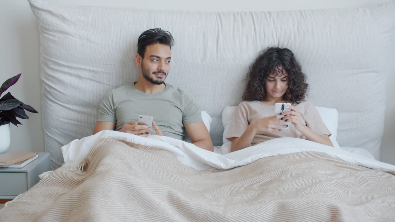 Couple Using Smartphones in Bed