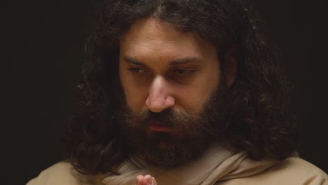 foto de cerca de un hombre vestido con túnicas con cabello largo y barba que representa la figura de jesucristo orando 2