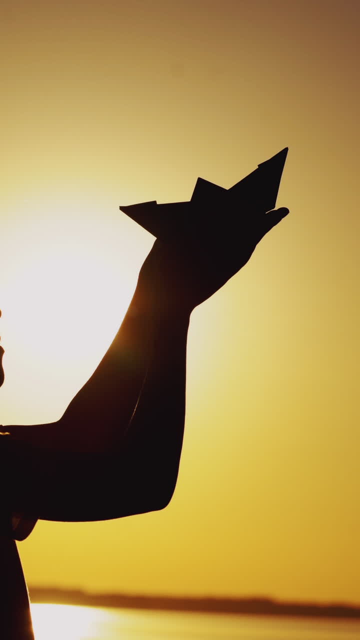 Paper boat is in the hands of a child. Beautiful summer sunset. Origami Vertical video