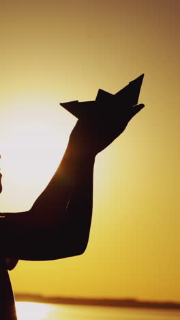 paper boat is in the hands of a child. beautiful summer sunset. origami vertical video
