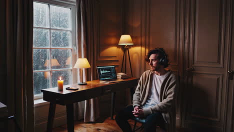 man listening to music at home office desk with laptop