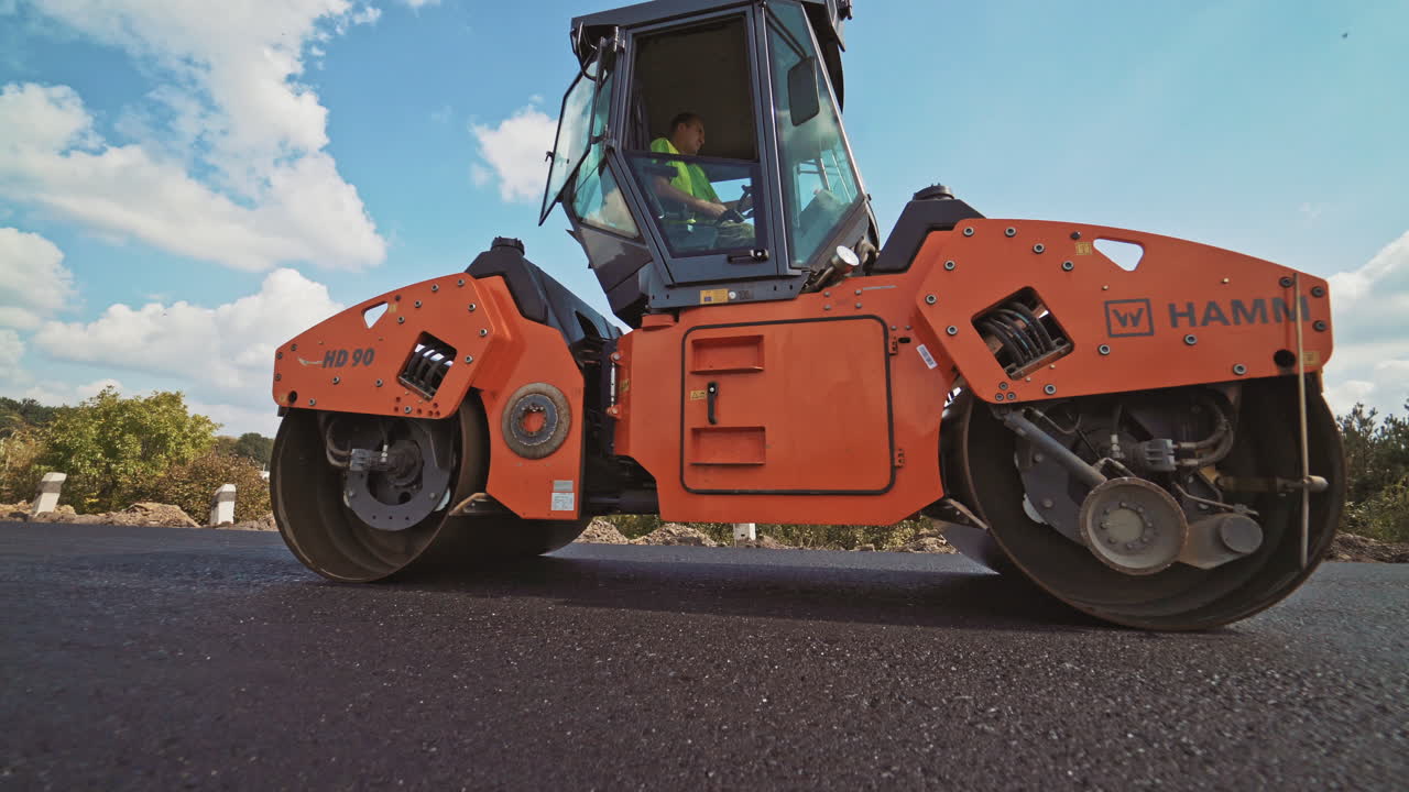 Laying a new asphalt on the road. Road repair machine with heavy vibration roller compactor