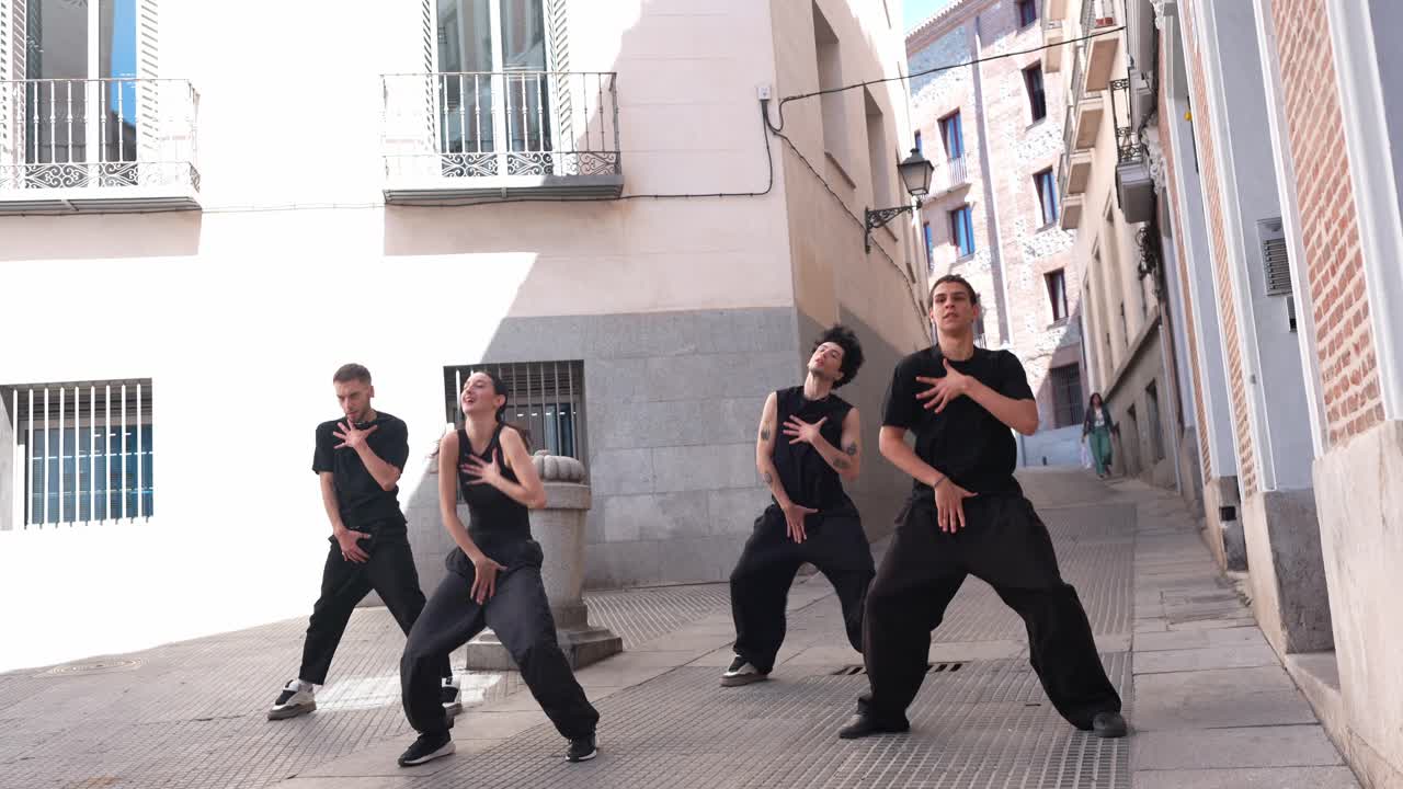 Gruppo di giovani ballerini che eseguono una coreografia su una strada urbana