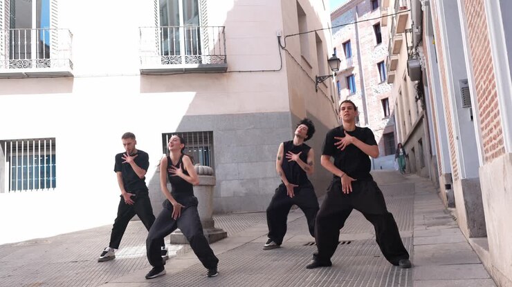 Gruppo di giovani ballerini che eseguono una coreografia su una strada urbana