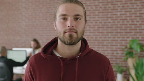 portrait of attractive young man in office internet cafe looking serious pensive at camera wearing hoodie