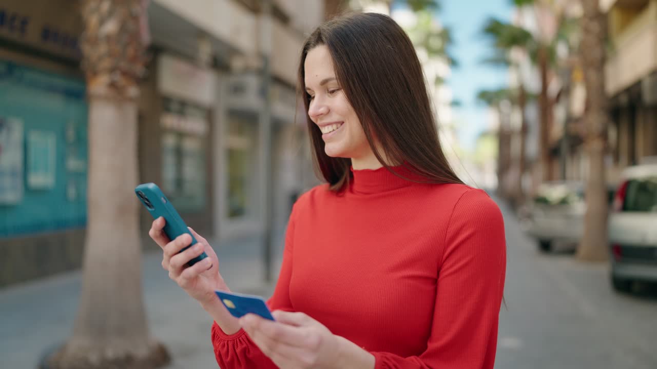 mujer joven usando teléfono inteligente y tarjeta de crédito en la calle