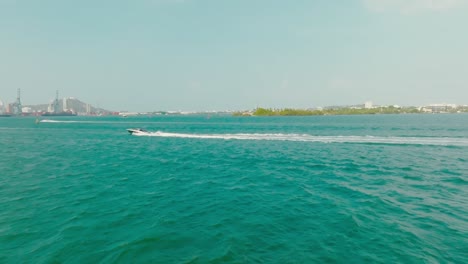 Aerial-Drone-shot-of-a-boat-in-the-ocean-passing-from-right-to-left-in-Colombia,-Cartagena