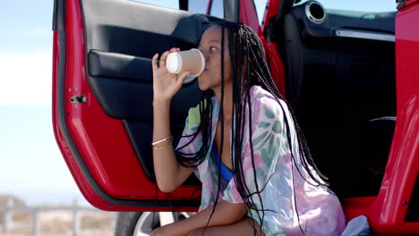 young african american woman enjoys a drink outdoors on a road trip