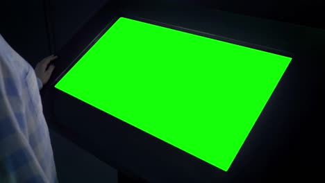 mujer mirando un quiosco de exhibición verde en blanco en una exposición - concepto de pantalla verde