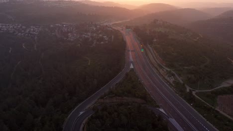 aerial view of an empty highway winding through hills at sunset
