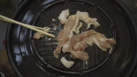 grilling meat on a mookata pan with chop sticks on thai style barbecue hotpot