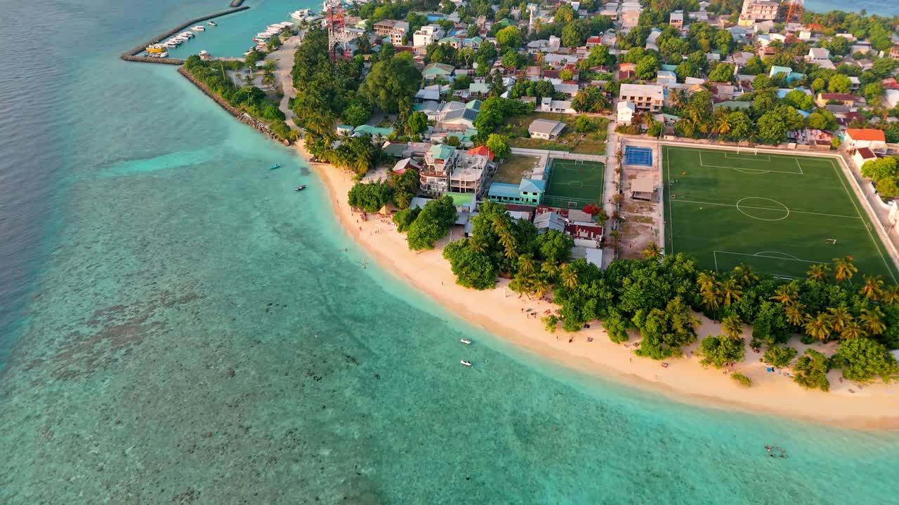 A breathtaking aerial drone view captures Rasdhoo Island bathed in the warm glow of sunset in the Maldives.