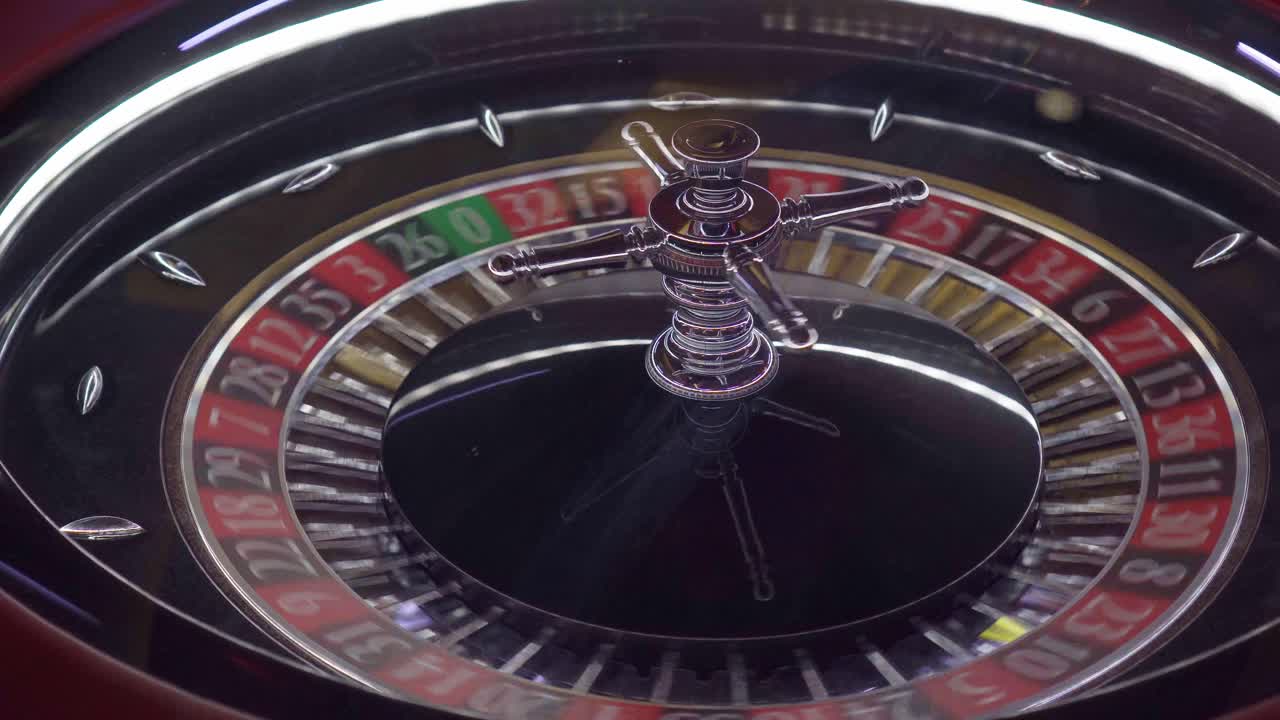 toma aérea de una rueda de ruleta de casino europeo girando y la pelota aterrizando en el número verde 0 donde el casino siempre gana