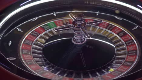 overhead shot of a european casino roulette wheel spinning and the ball landing on the green number 0 where the casino always wins