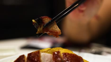 chopsticks holding duck over sliced roast chicken