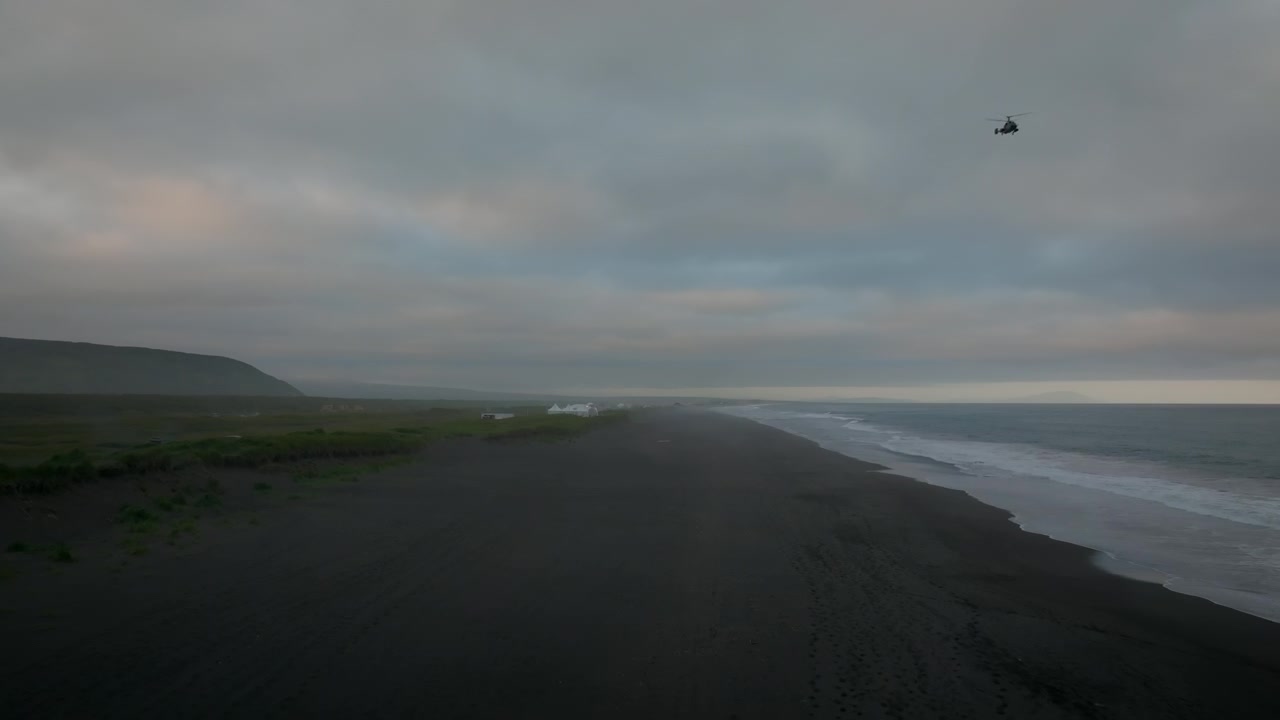 Drone footage of Khalaktyrsky Beach black volcanic sand shoreline and Pacific Ocean waves under overcast sky, Kamchatka Krai, Russia, remote nature travel scene