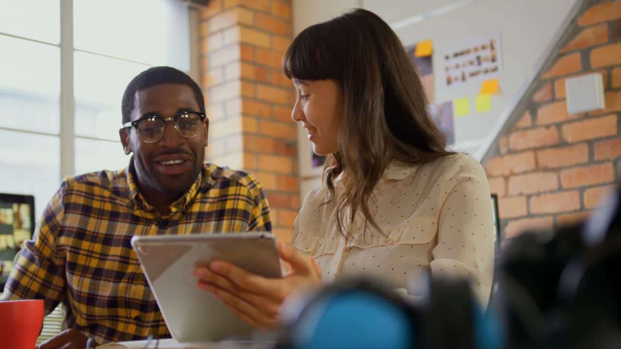 Graphic designers discussing over digital at desk in a modern office 4k