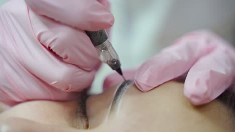 master is making permanent make-up of eyebrows with professional needle. eyebrows shape correction. cosmetology