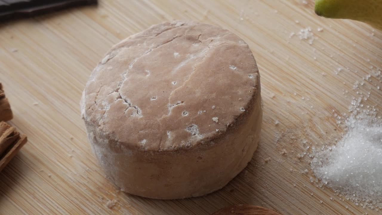 Round traditional Spanish sweet treat on a wooden cutting board, sprinkled with powdered sugar