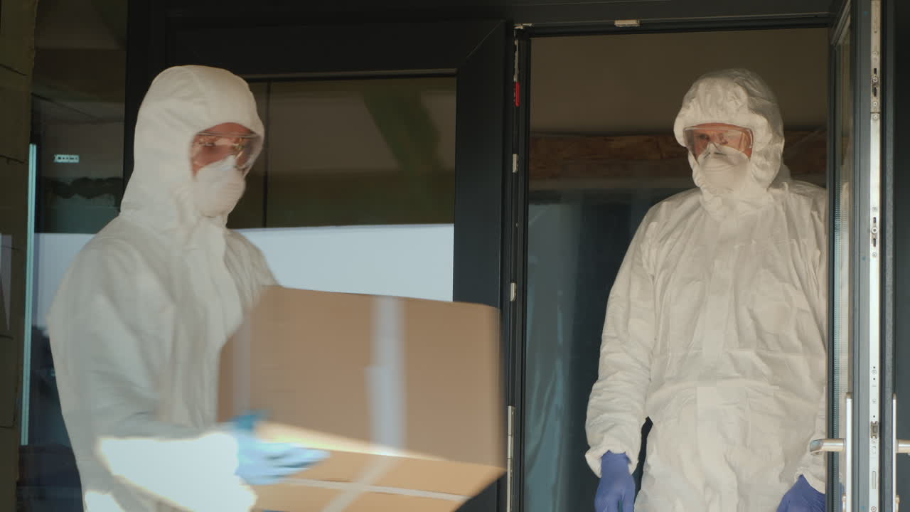 hombres con trajes de protección biológica cargan cajas de medicamentos en el almacén del hospital