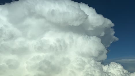 awesome aerial view of the top of a massive storm cumulonimbus cloud shot from a jet cabin during the cruise level