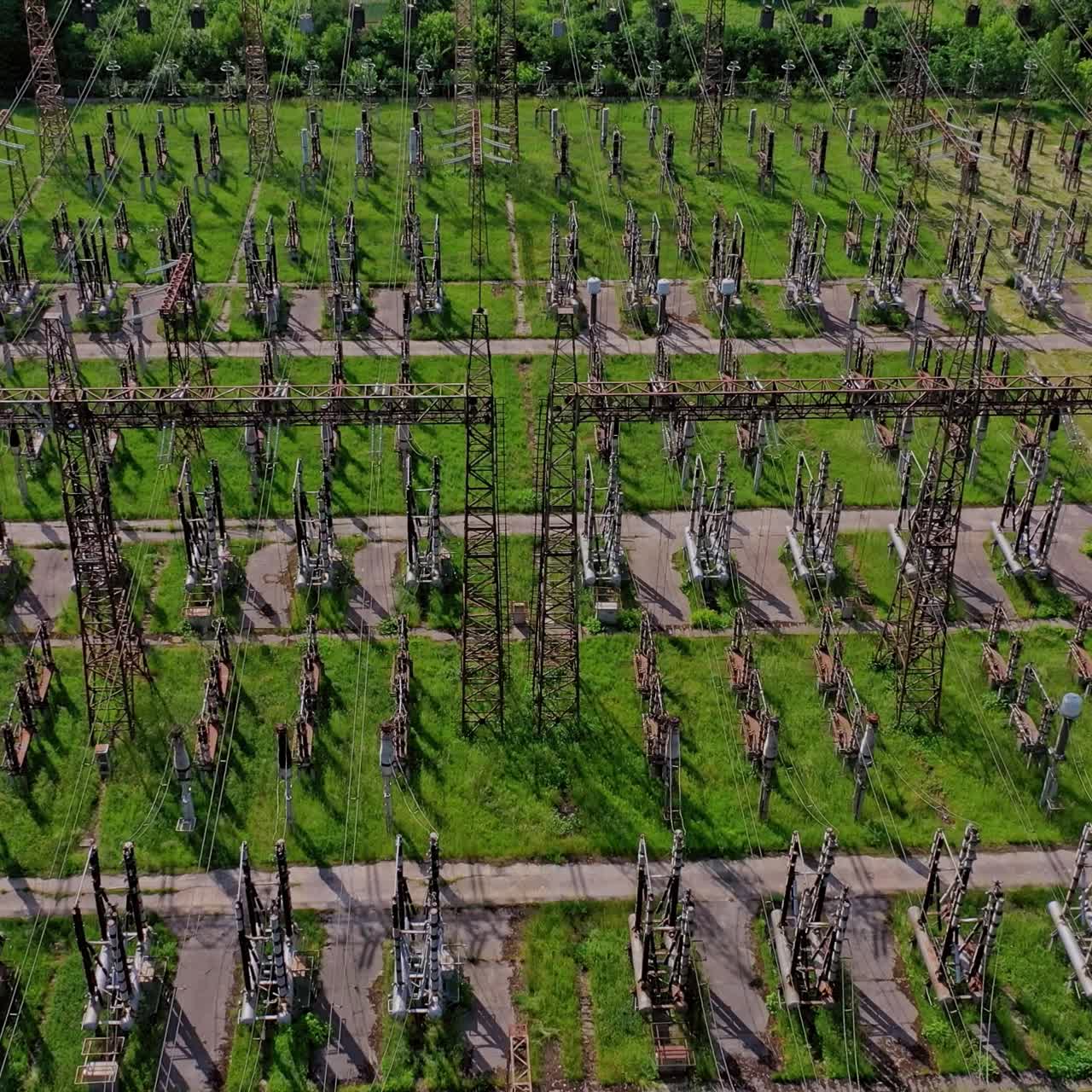 Electric supports among green field.Flight over huge field with high voltage steel pylons. High voltage lines in nature. Aerial view.