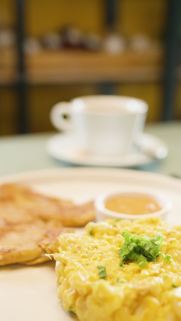 Breakfast plate with mote pillo, accompaniments and sauce in the foreground, with a cup of coffee and roast meat out of focus in the background