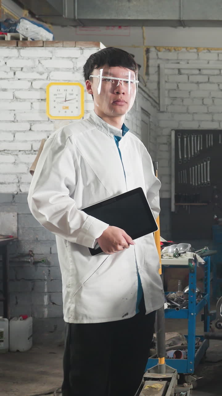 dos inventores con abrigos de laboratorio y gafas de protección de pie cerca de un motor en el taller mecánico, sosteniendo tabletas para el registro de datos, la luz de fondo brillante destaca el espacio de trabajo industrial