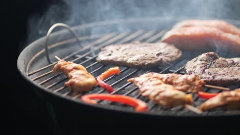 slow motion shot of a grill with steak, chicken skewers, peppers and salmon