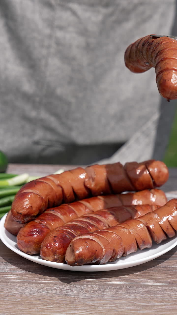 Human hands taking fried juicy sausage. Man prepairing meal for picnic. Vertical video