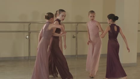 a group of young ballet students in black dancewear practicing positions in a spacious ballet studio with wooden flooring and wall-mounted barres. focused expressions and synchronized movements.