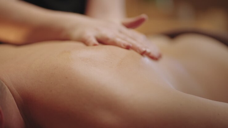 massage for male client in spa salon or osteopathic clinic woman masseuse is massaging back of young man