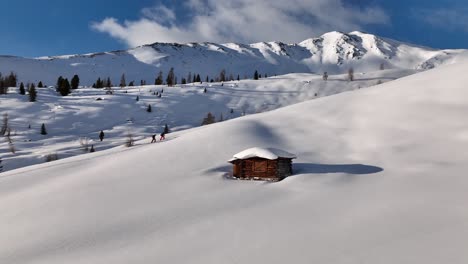 Two-backcountry-skiers-passing-an-old-hut-on-the-ascent