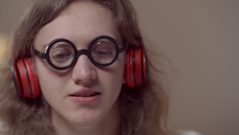 close-up portrait of young brunette man with long curly hair listening to music in headphones and singing. headshot of carefree relaxed caucasian nerd enjoying playlist indoors in 1980s 1990s