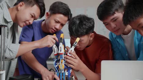 group of young asian boys with a laptop and 3d printing helping each other repairing a cyborg hand at home