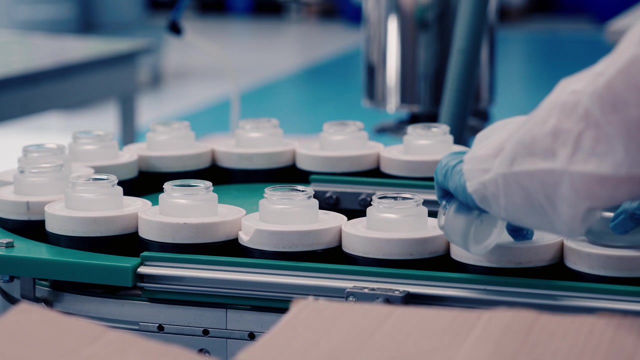 Filling bottles with cosmetic cream in a factory, assembly line work
