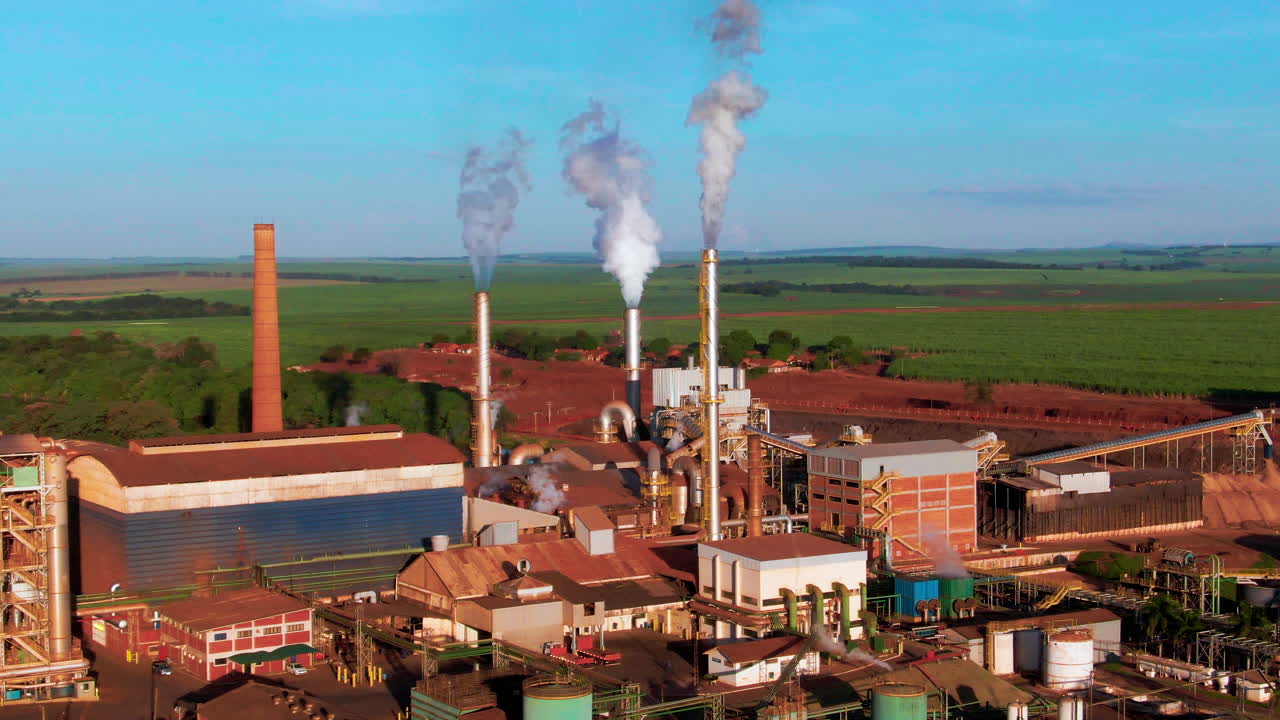 Drone aerial landscape of steam turbines and ethanol production plant facility factory buildings in rural countryside farmland valley of Brazil South America industry emissions processing environment