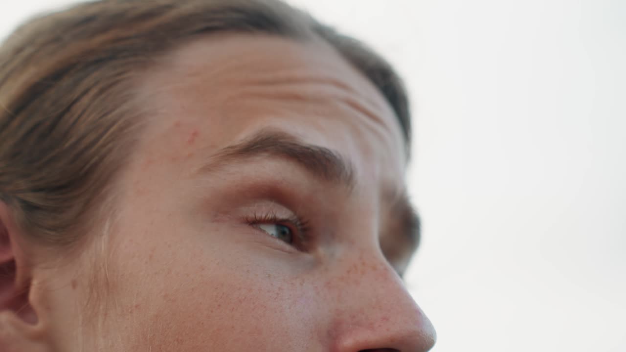 Individual contemplates faraway landscape view. Caucasian man with lengthy hair considers distant scenery outdoors. Closeup of freckled male gazing thoughtfully towards horizon in nature